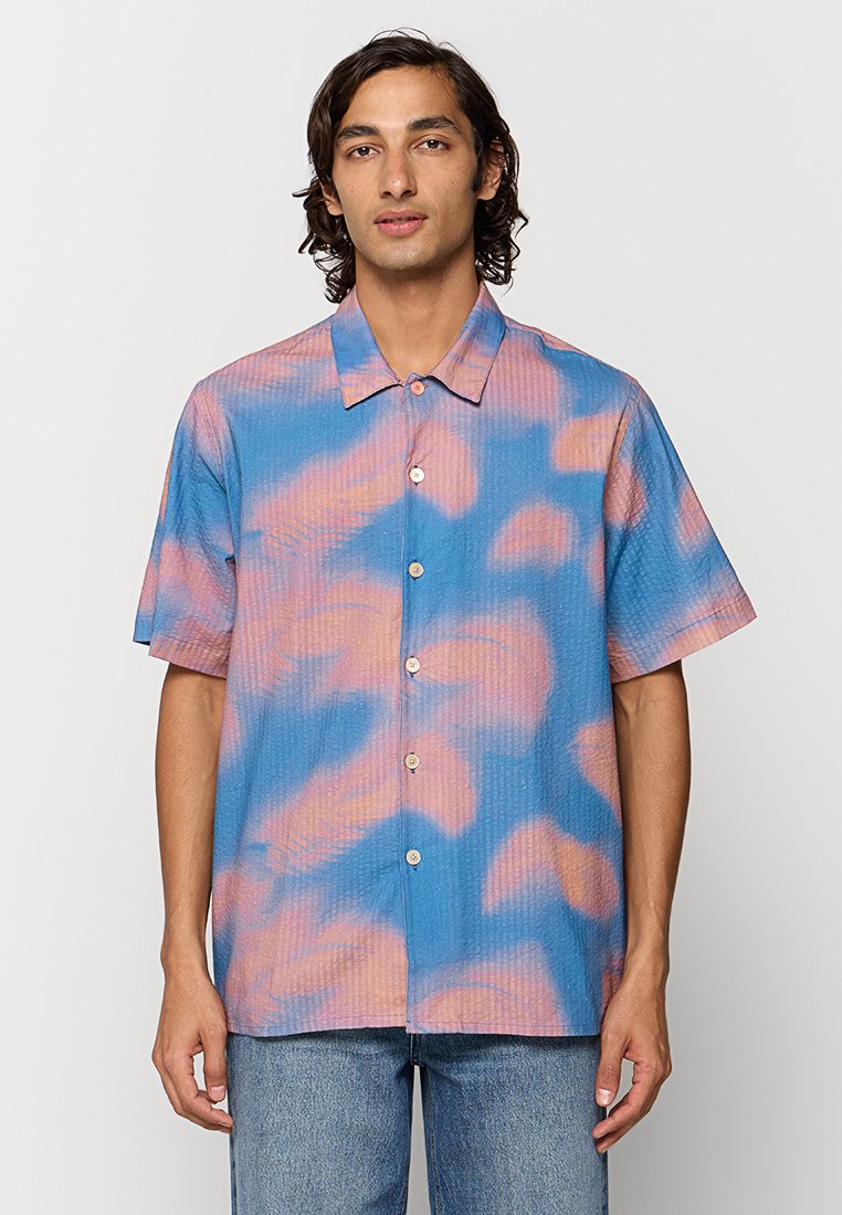 Hemd mit kurzen Ärmeln in Hellblau mit pinkem abstraktem Muster, verfügt über eine Knopfleiste und ein strukturiertes Material. Trägt es mit Jeans.