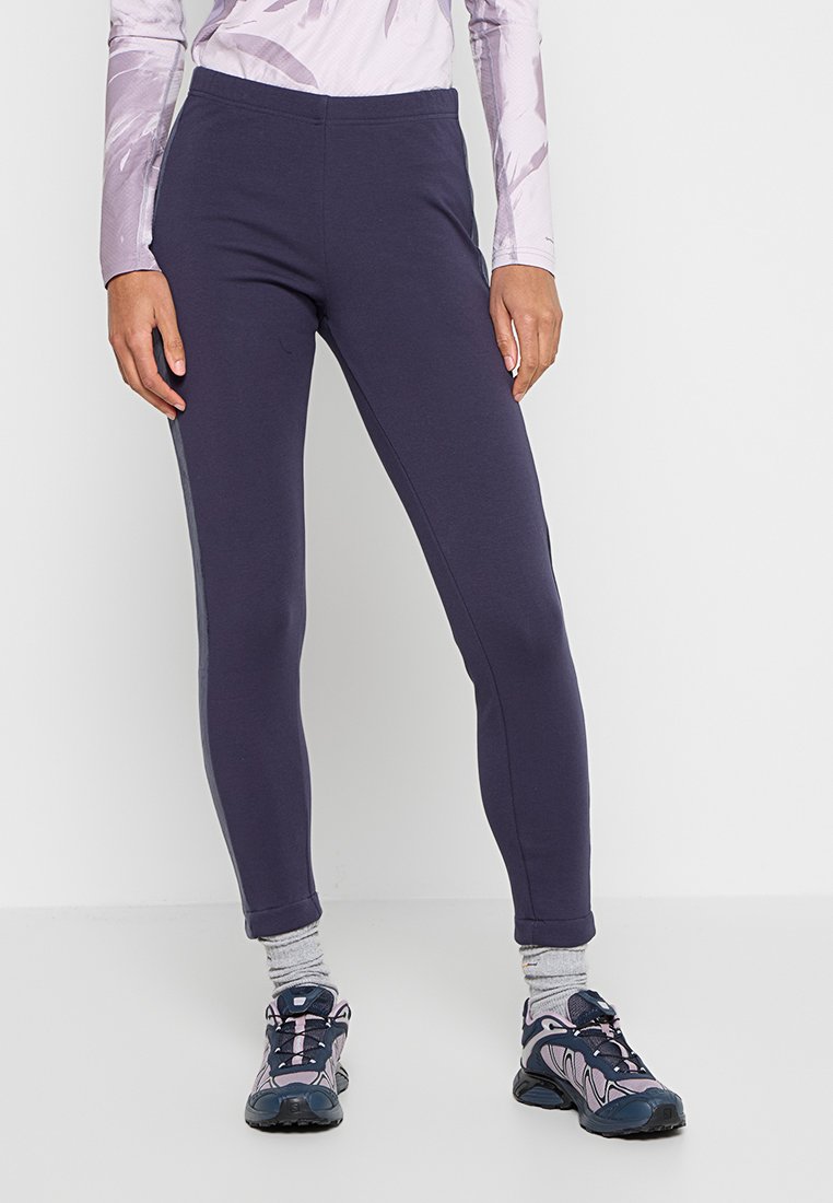 Marineblaue sportliche Leggings aus weichem Stoff, mit figurbetontem Schnitt, glatter Textur und einem mittelhohen Bund. Kombiniert mit grauen Socken und Turnschuhen.