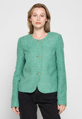 Texturierte grüne Jacke mit rundem Halsausschnitt, drei goldenen Knöpfen, taillierter Passform und langen Ärmeln. Über dunklen Hosen getragen.