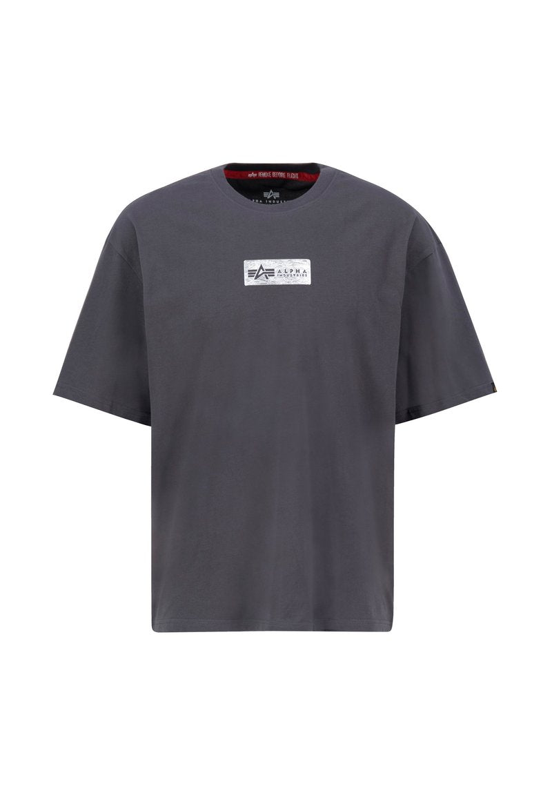 Graues Baumwoll-T-Shirt mit kurzen Ärmeln, Rundhalsausschnitt und einem rechteckigen weißen Etikett mit schwarzem Logo auf der Brust. Glatte Textur.