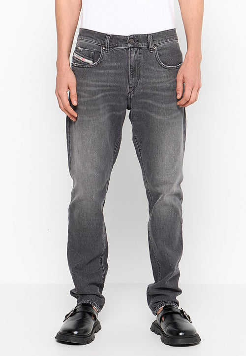 Graue Jeans aus Denim mit einem ausgewaschenen Design, im Fünf-Taschen-Stil und mit Gürtelschlaufen. Getragen mit schwarzen Schuhen, die ein Schnallendetail aufweisen.