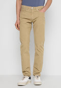 Beige Baumwollhosen mit geradem Bein, fünf Taschen und einer subtilen Textur, kombiniert mit weißen und marineblauen Sneakers.