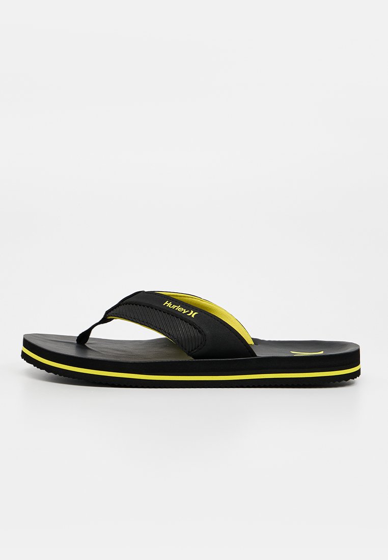 Schwarze und gelbe Hurley Flip-Flop-Sandale mit dickem Riemen und strukturierter Sohle, gezeigt vor einem schlichten weißen Hintergrund.