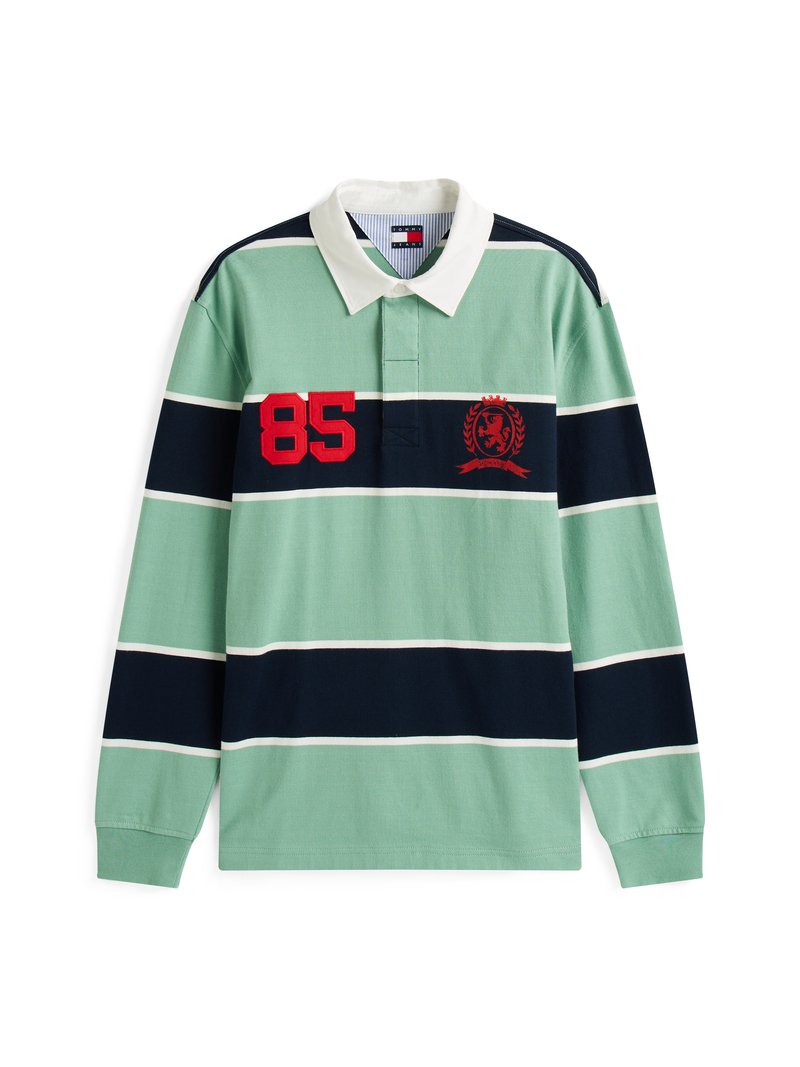 Langärmliges Poloshirt mit grün-blau gestreiftem Design. Es verfügt über einen weißen Kragen, die rote Zahl "85" und ein besticktes Wappen auf der Brust.