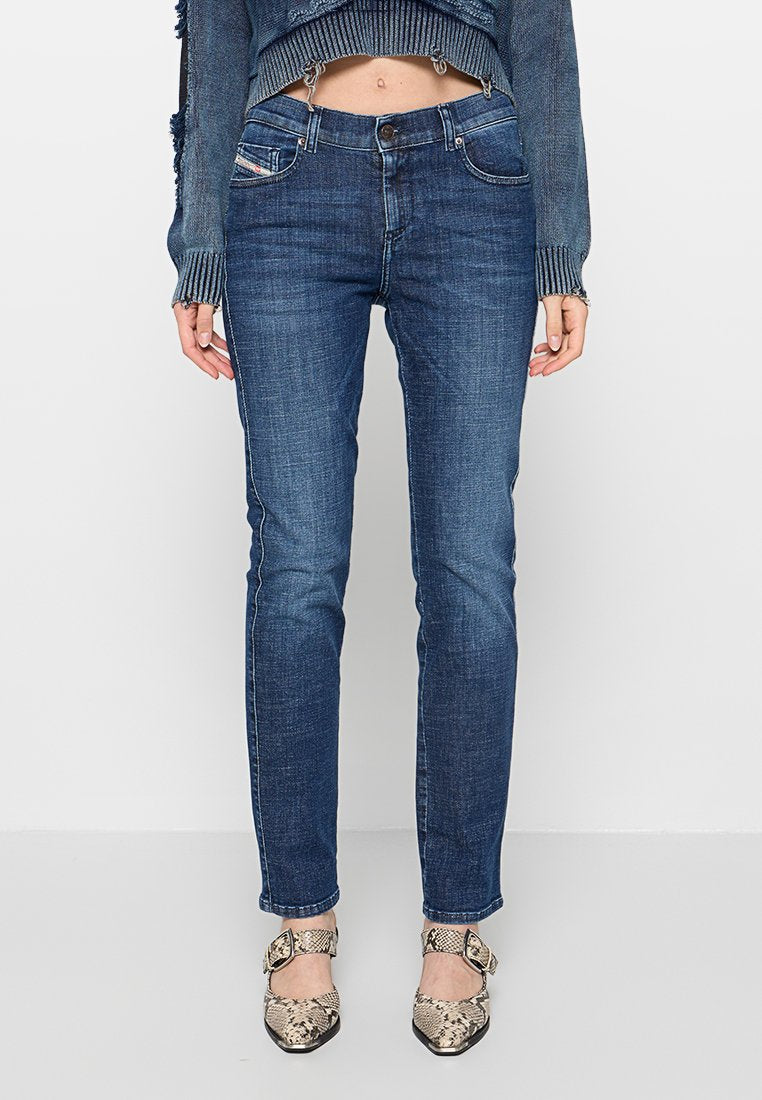 Blaue Jeans im Slim Fit mit fünf Taschen, heller Naht und Knopfverschluss. Kombiniert mit gemusterten High Heels.