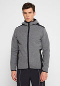 Junger Mann, der einen grauen Reißverschluss-Hoodie mit schwarzen Akzenten und schwarze Hosen trägt, steht vor einem schlichten weißen Hintergrund.