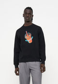 Mann trägt einen schwarzen Sweatshirt mit einer Neon-Style-Grafik eines orangen Getränks mit rotem Strohhalm, kombiniert mit hellgrauen Hosen.