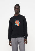 Mann trägt einen schwarzen Sweatshirt mit einer Neon-Style-Grafik eines orangen Getränks mit rotem Strohhalm, kombiniert mit hellgrauen Hosen.