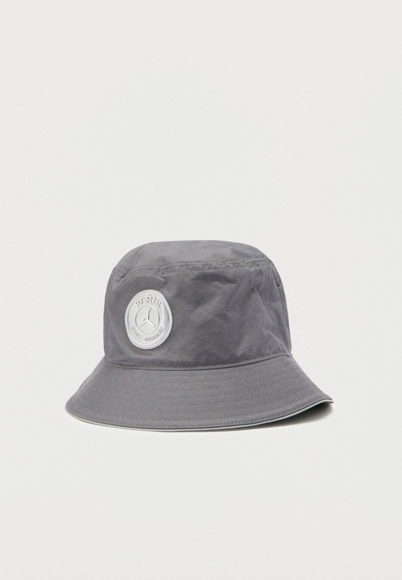 Grauer Bucket-Hut aus wasserabweisendem Stoff, mit einem runden Logo-Patch auf der Vorderseite und einer breiten, nach unten geneigten Krempe.