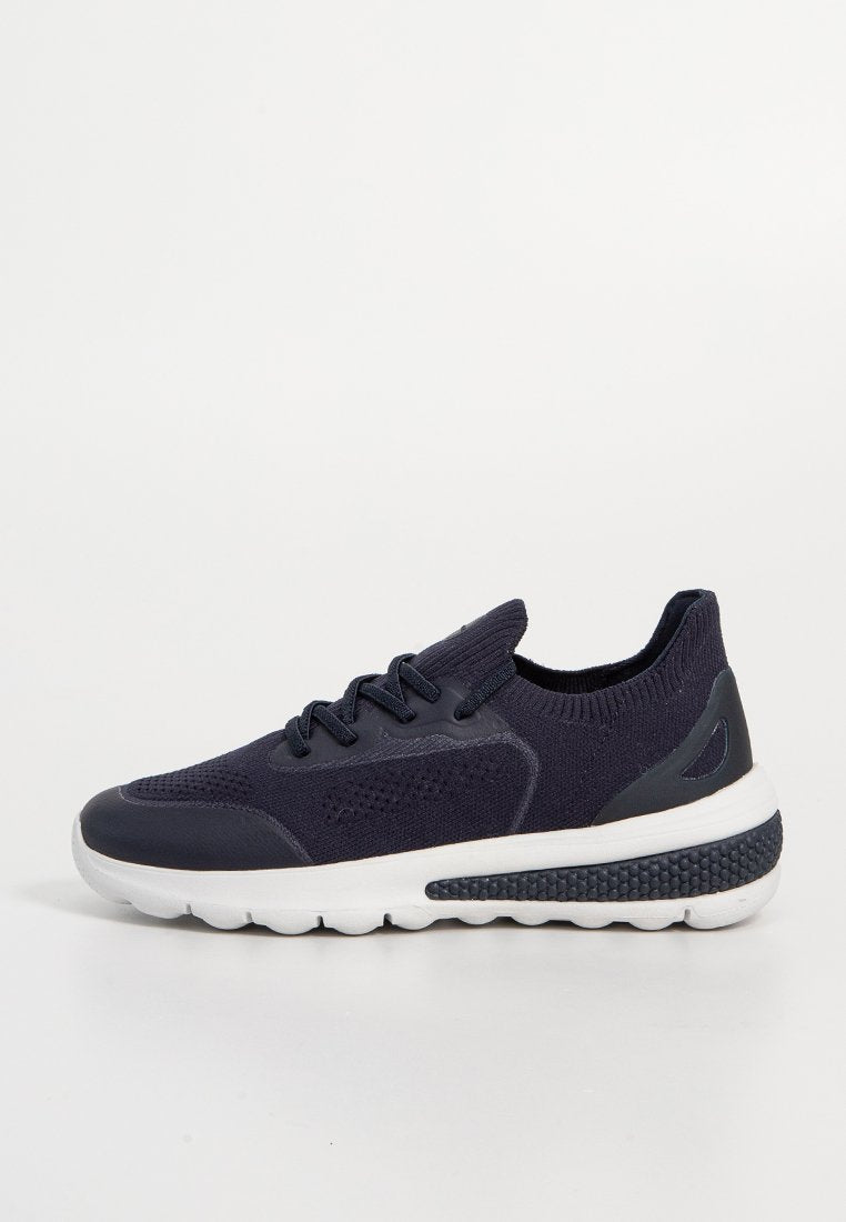 Marineblaue Sportschuhe mit einem atmungsaktiven Strickobermaterial, einer strukturierten Gummisohle und einer kontrastierenden weißen Zwischensohle. Sie verfügen über Schnürsenkel und einen gepolsterten Schaft.