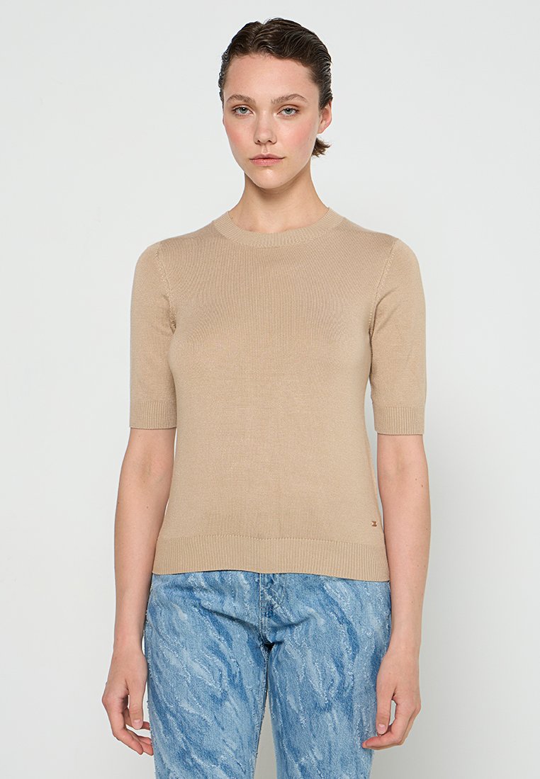 Beige gestrickter Pullover mit kurzen Ärmeln und rundem Halsausschnitt; hat eine figurbetonte Silhouette und ein kleines Logodetail am Saum.