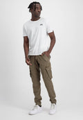Weißes T-Shirt mit kurzen Ärmeln und kleinem schwarzem Logo, kombiniert mit olivgrünen Cargo-Hosen mit mehreren Taschen und schmalem Schnitt. Weiße Sneakers.