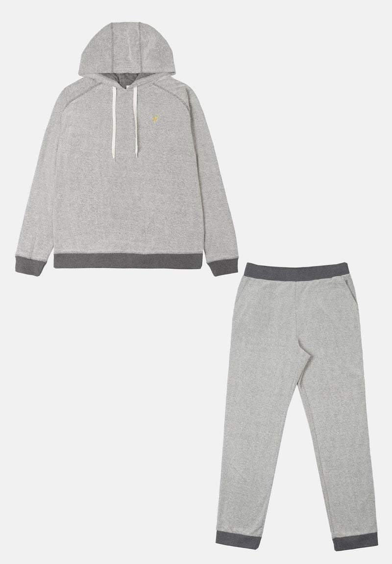 Grau-gestreiftes Loungewear-Set bestehend aus einem Kapuzenoberteil mit weißen Kordeln und passenden schmal zulaufenden Hosen mit dunkler grauen Bündchen. Strukturierter Stoff.