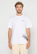 Mann trägt ein weißes T-Shirt mit kurzen Ärmeln, auf dem sich nahe der linken Brust ein kleines schwarzes und blaues grafisches Textmuster sowie grafische Tags in der Nähe der rechten Hüfte befinden.