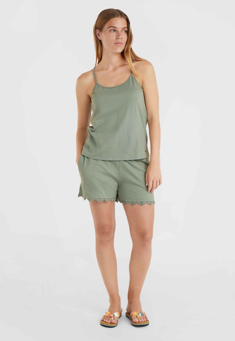 Olivgrünes Trägertop mit dünnen Trägern, kombiniert mit passenden Shorts mit gewählten Kanten. Das Model trägt farbige Flip-Flops.
