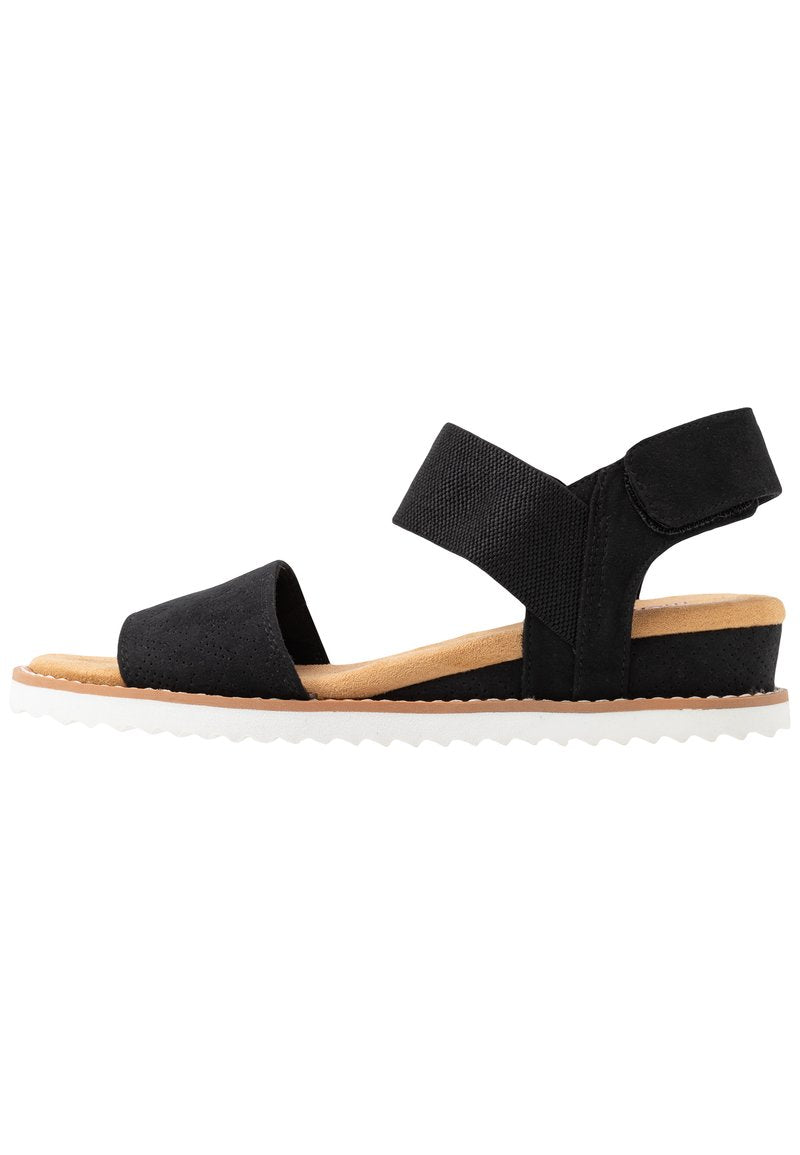 Schwarze Sandalen mit Textilriemen, einer weichen, hellbraunen Innensohle und einer weißen, strukturierten Außensohle. Verfügt über zwei breite verstellbare Riemen für zusätzlichen Komfort.