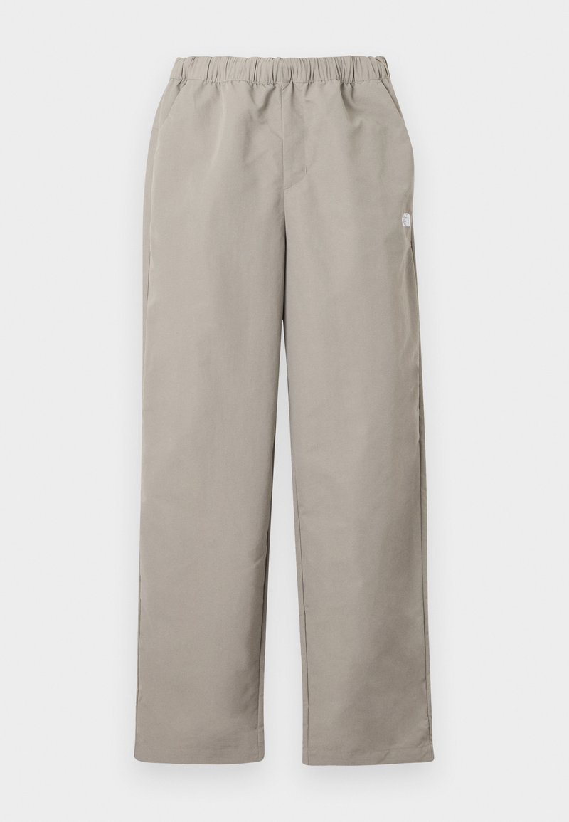 Beige gerade geschnittene Hose mit elastischem Bund und kleinem weißem Logo an der rechten Seitennaht.