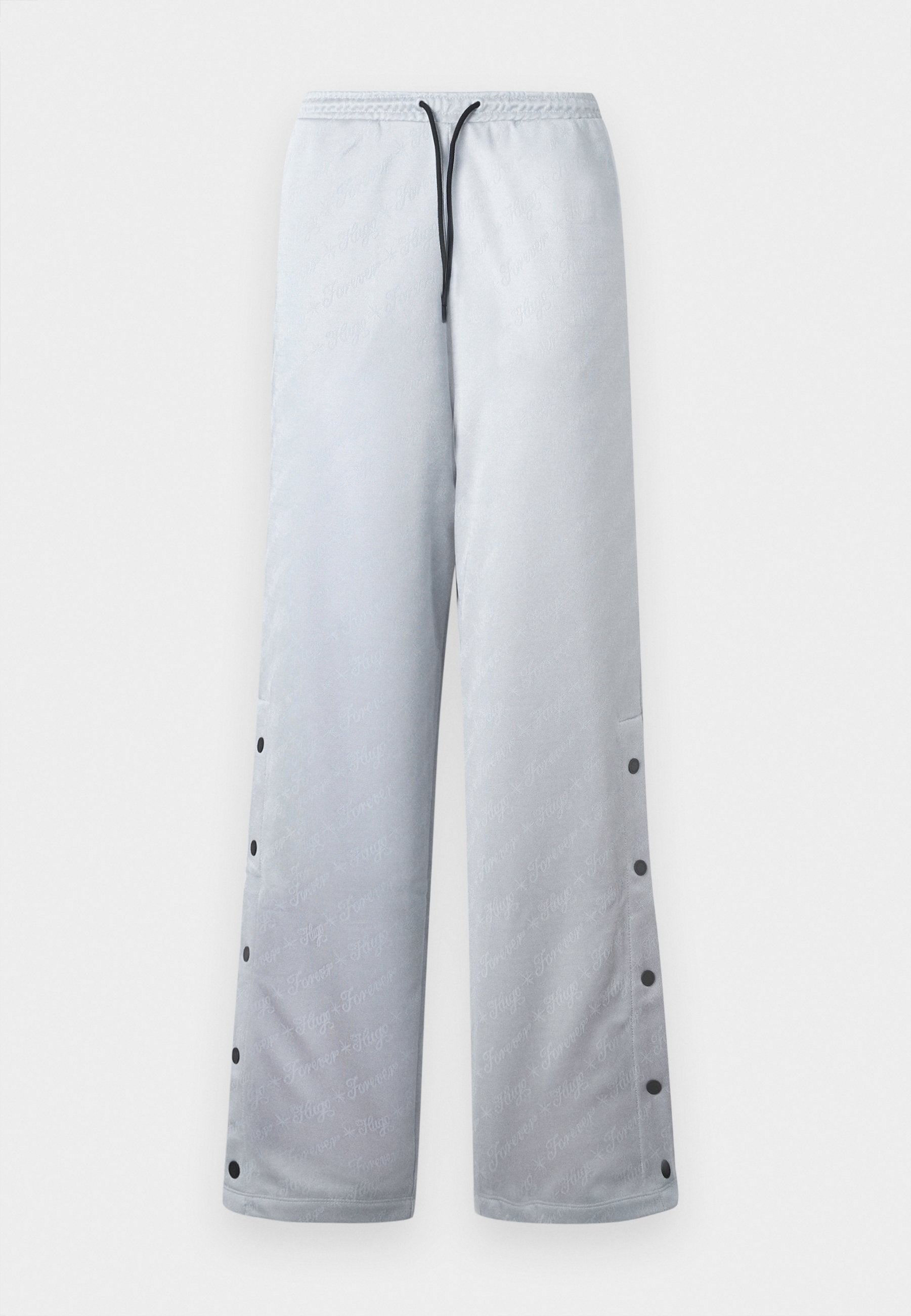 Hellgraue Jogginghose mit glänzender Textur, ausgestattet mit einem elastischen Bund, schwarzem Kordelzug und Druckknöpfen entlang der Seitennaht.