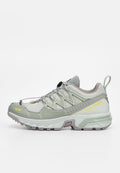 Hellgrauer und weißer Trailrunning-Schuh mit strukturierter Sohle, Schnellverschluss-System und gelbem Salomon-Logo an der Seite.