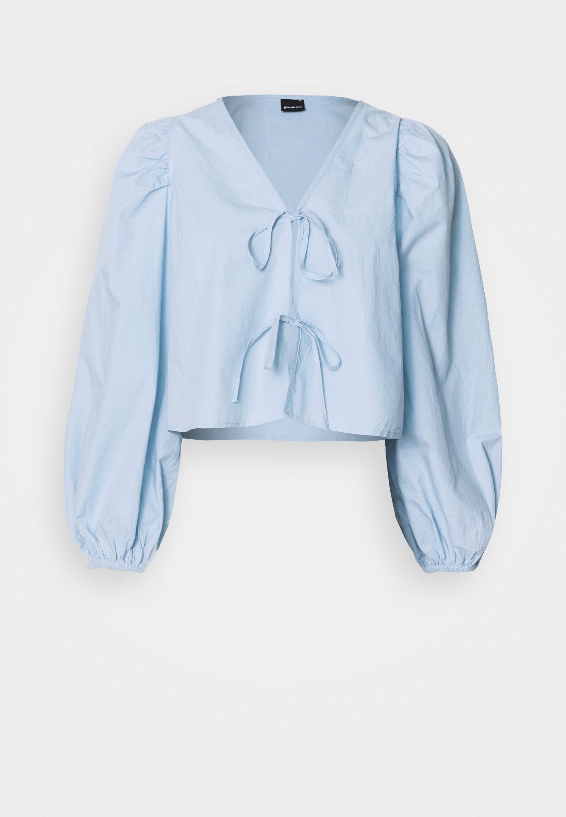 Hellblaues, kurz geschnittenes Blusenshirt mit V-Ausschnitt, Bindeschluss und Puffärmeln. Hergestellt aus glattem Stoff mit elastischen Bündchen.