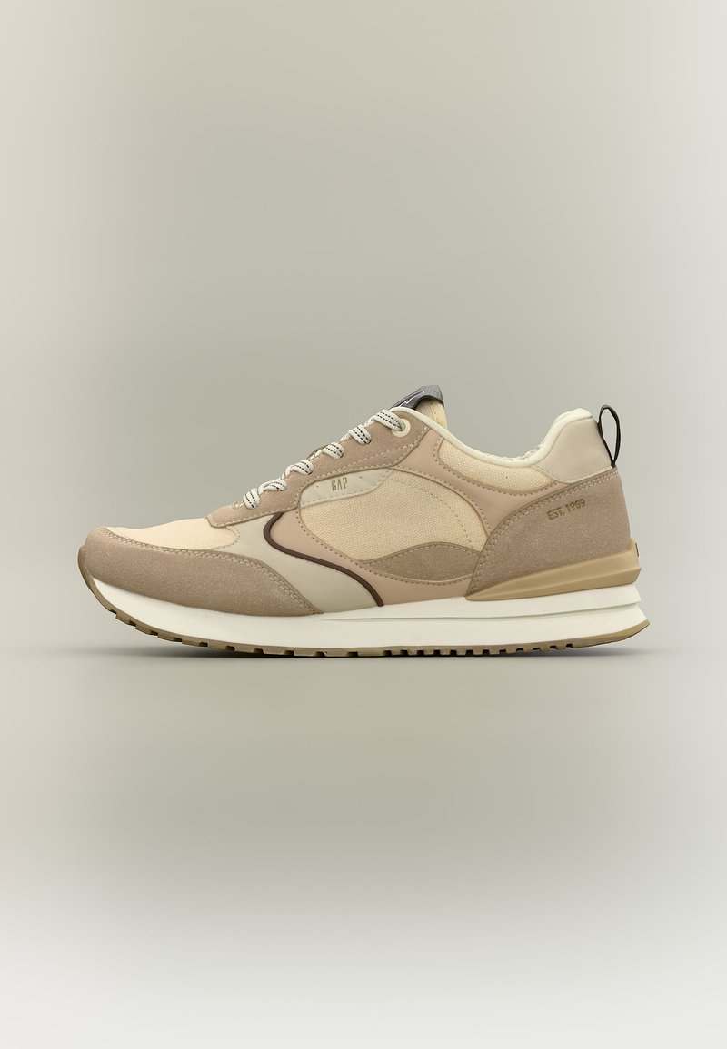 Beige und brauner Sneaker mit weißer Sohle, Mesh- und Wildlederpaneelen, Schnürsenkeln, "GAP"-Logo nahe den Schnürsenkeln und "EST. 1969" an der Ferse.