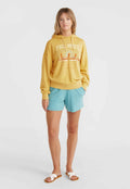 Gelbes Sweatshirt mit grafischem Druck, kombiniert mit hellblauen Shorts und weißen Schlüpfsandalen. Lässiger Schnitt und weicher Stoff.