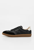 Schwarzer Sneaker aus Leder und Velours mit niedrigem Schaft, Gummisohle und weißem Fersenriemen, mit "AIGNER"-Branding an der Seite.