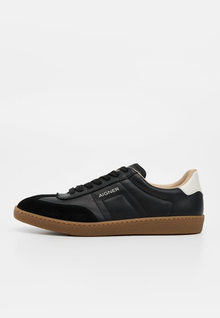 Schwarzer Sneaker aus Leder und Velours mit niedrigem Schaft, Gummisohle und weißem Fersenriemen, mit "AIGNER"-Branding an der Seite.