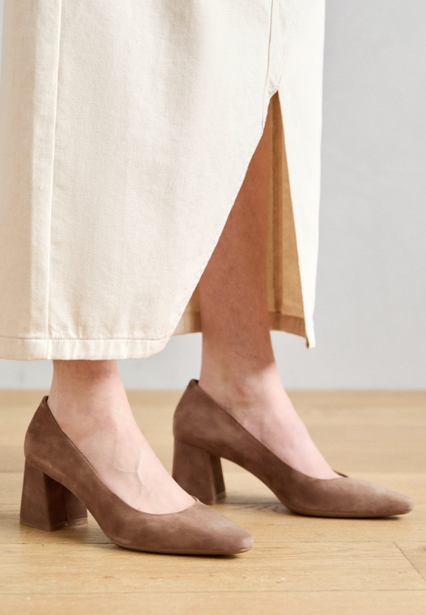 Braune Wildleder-High-Heels mit runder Zehe und quadratischem Blockabsatz, getragen mit einem hellen Rock.