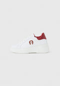 Weißer Plateausneaker mit rotem Fersenlasche, rotem Logo an der Seite und weißen Schnürsenkeln auf einem schlichten hellgrauen Hintergrund.