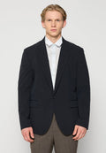 Marineblauer Blazer aus strukturiertem Stoff, mit einem einzelnen Knopfverschluss und zwei Fronttaschen, getragen über einem hellblauen Hemd und braunen Hosen.
