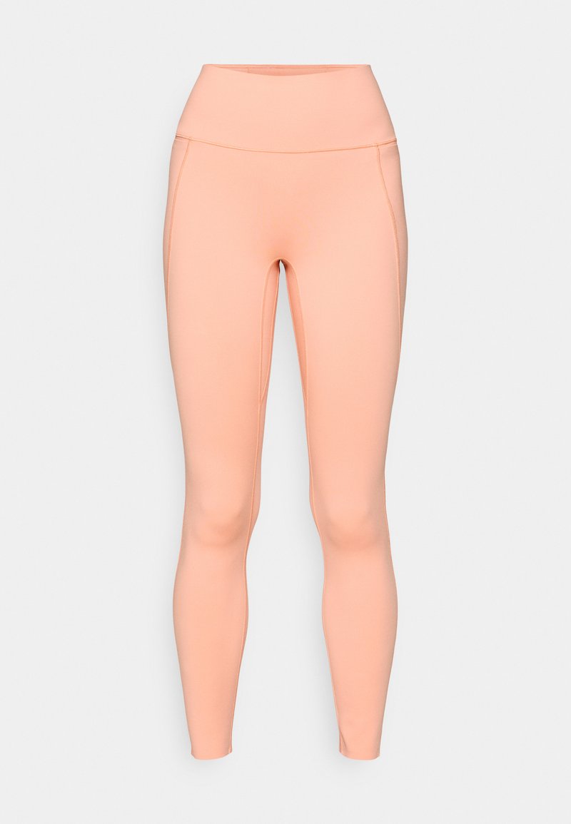 Pfirsichfarbene Leggings aus elastischem Material, mit einem hohen Bund, glatter Textur und nahtlosem Design ohne sichtbare Taschen.