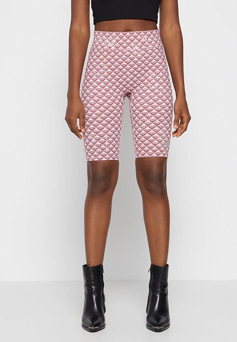 Rosa gemusterte Radlerhosen mit einer Diamantstruktur, hoch geschnittenes Design, aus dehnbarem Material, kombiniert mit schwarzen Knöchelstiefeln.