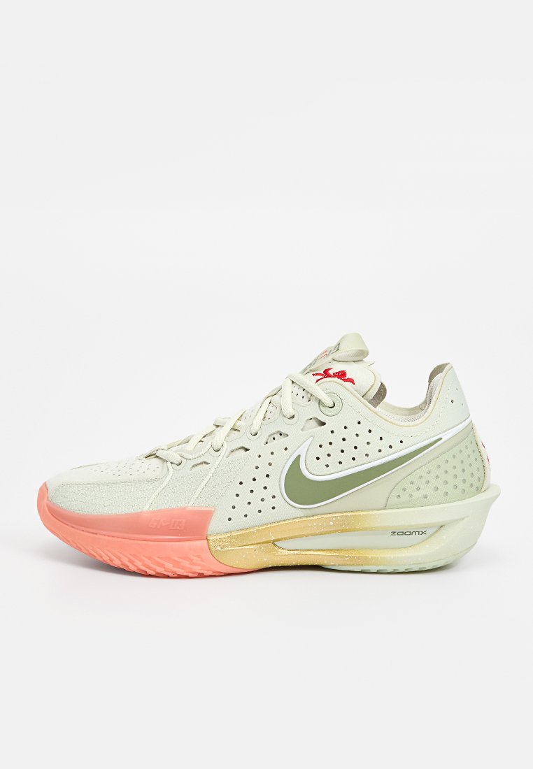 Nike Sportschuh mit einem hellbeigen Mesh-Obermaterial, Belüftungslöchern, grünem Swoosh, pinken und gelben Akzenten an der Sohle sowie gepolstertem Design.