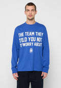Blaues langärmeliges T-Shirt aus Baumwolle mit großem weißen Text auf der Vorderseite. Der Text lautet: "THE TEAM THEY TOLD YOU NOT T'WORRY ABOUT."
