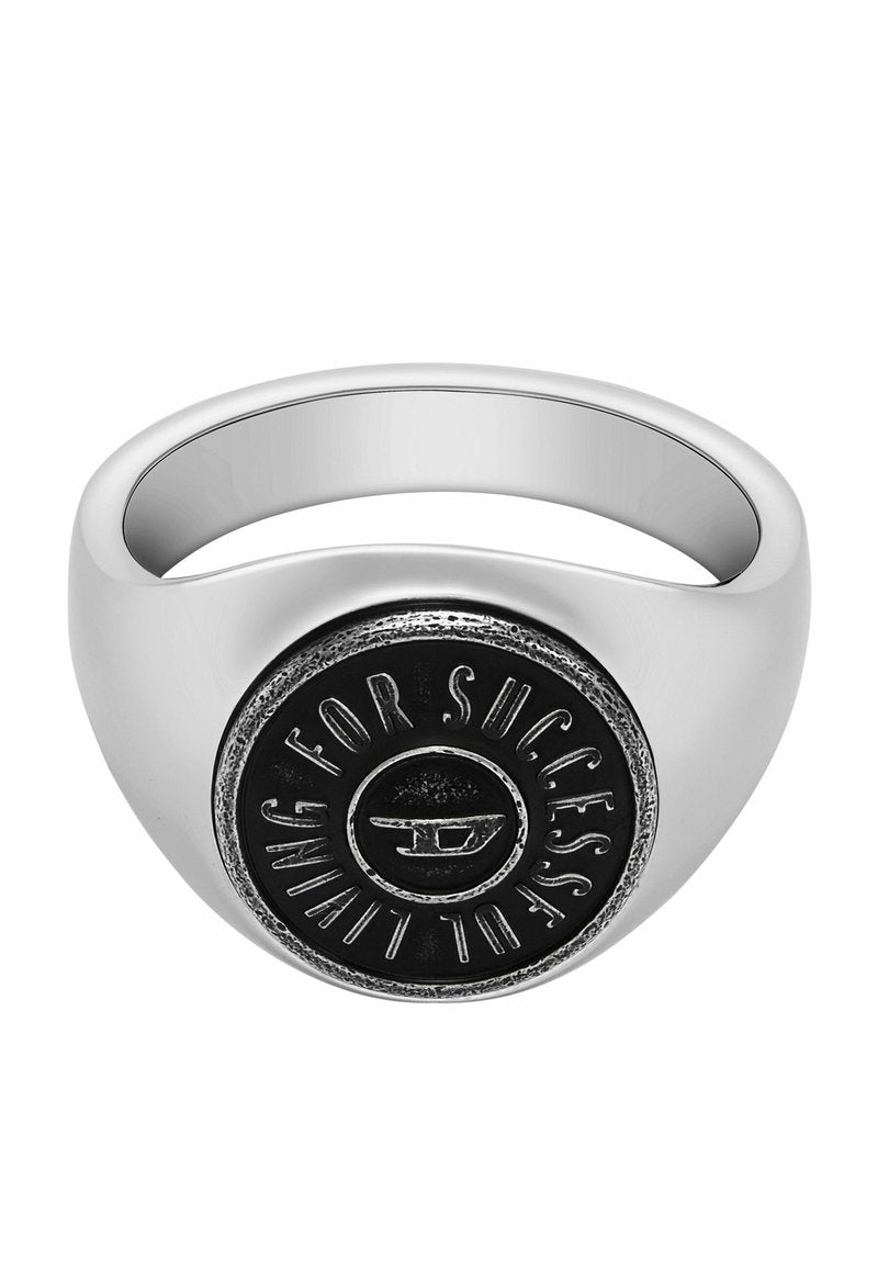 Silberner Ring mit einem abgerundeten Band, das ein auffälliges schwarzes kreisförmiges Emblem aufweist, in das "FÜR ERFOLG" und ein Logo-Motiv in der Mitte eingraviert sind.