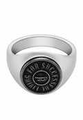 Silberner Ring mit einem abgerundeten Band, das ein auffälliges schwarzes kreisförmiges Emblem aufweist, in das "FÜR ERFOLG" und ein Logo-Motiv in der Mitte eingraviert sind.