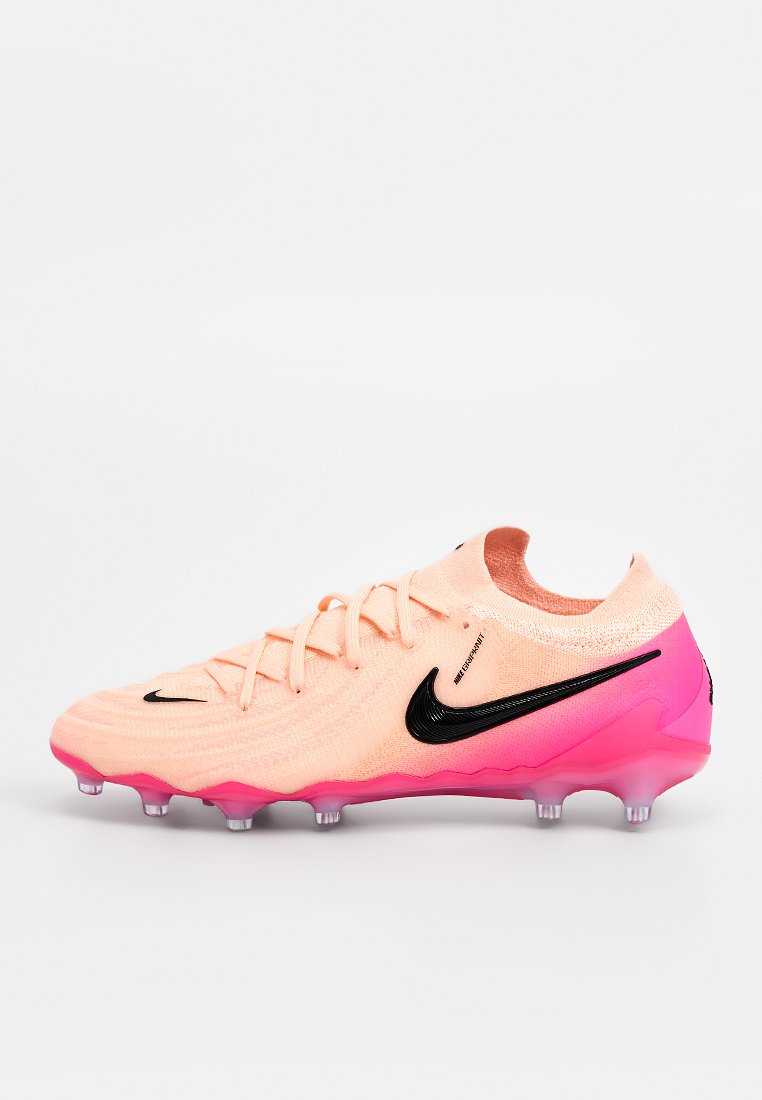 Nike-Fußballschuh mit strukturiertem apricotfarbenem Obermaterial, schwarzem Swoosh-Logo und einer Verlaufssohle in Pink. Ausgestattet mit Schnürsenkeln und transparenten Stollen.