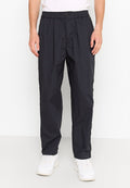 Schwarze, leichte, tapered Hosen mit einem elastischen Bund, Knopfverschluss und seitlichen Taschen. Getragen mit weißen Turnschuhen.