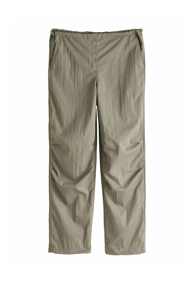 Leichte, khakifarbene Hose mit elastischem Bund, seitlichen Taschen und einem strukturierten Stoff. Gerader Schnitt mit minimalen Details.