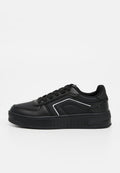 Schwarze Sneaker aus synthetischem Material, mit perforierter Textur, Schnürdesign, kontrastierenden weißen Akzenten und dicker Sohle.