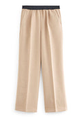 Beige weite Hosen mit einem schwarzen elastischen Bund, seitlichen Taschen und einer glatten Textur, die einen lockeren Sitz und ein maßgeschneidertes Design präsentieren.