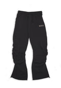 Schwarze, leichte, elastische Hosen mit einem Kordelzugbund, die geraffte Details und ein kleines Logo-Element an der Seite aufweisen.