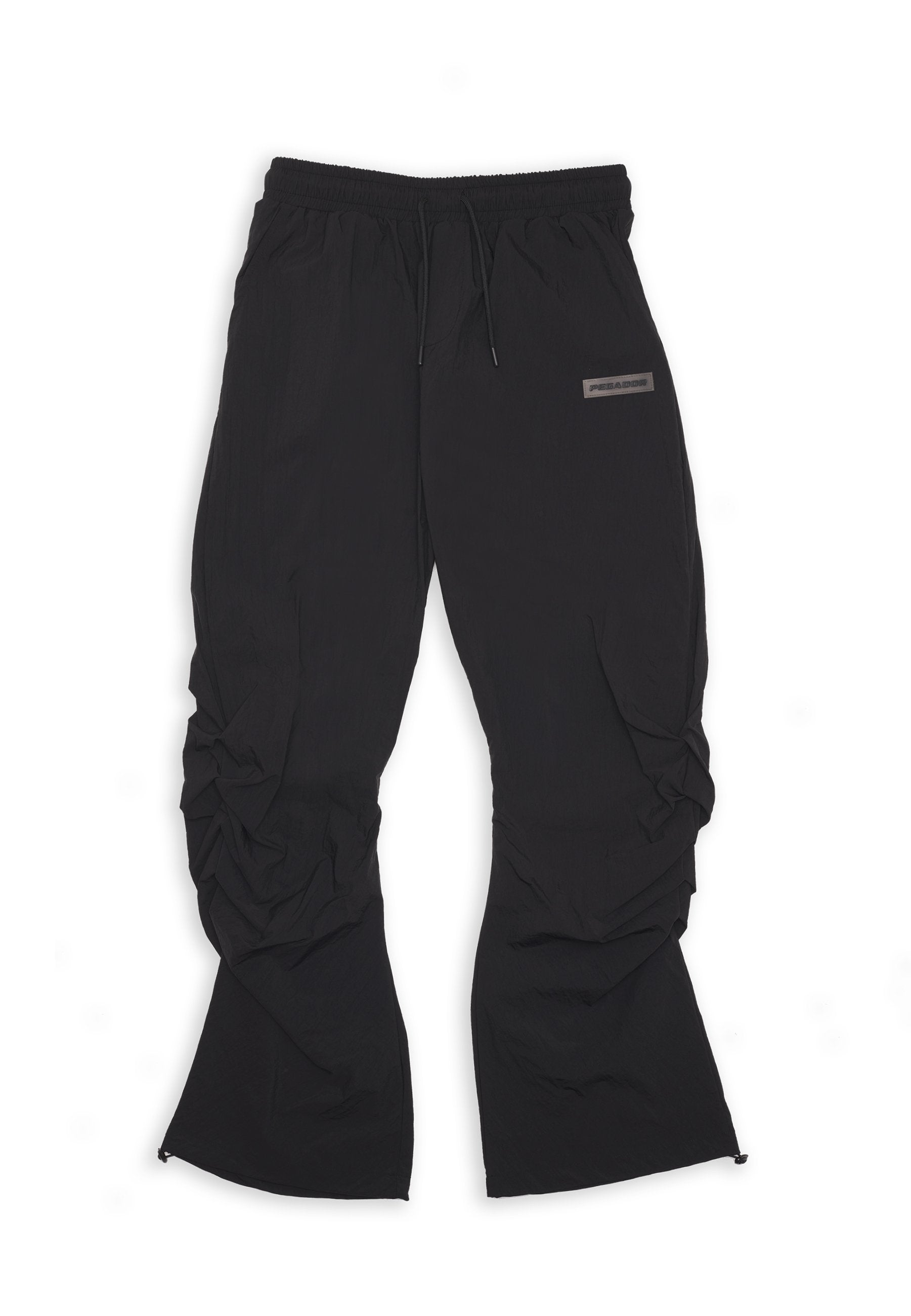 Schwarze, leichte, elastische Hosen mit einem Kordelzugbund, die geraffte Details und ein kleines Logo-Element an der Seite aufweisen.