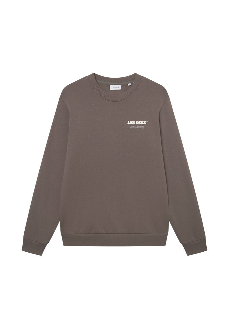 Brauner Sweatshirt aus weichem Stoff, mit langen Ärmeln, Rundhalsausschnitt und einem weißen Logo auf der Brust. Gerippte Ärmelbündchen und Saum.