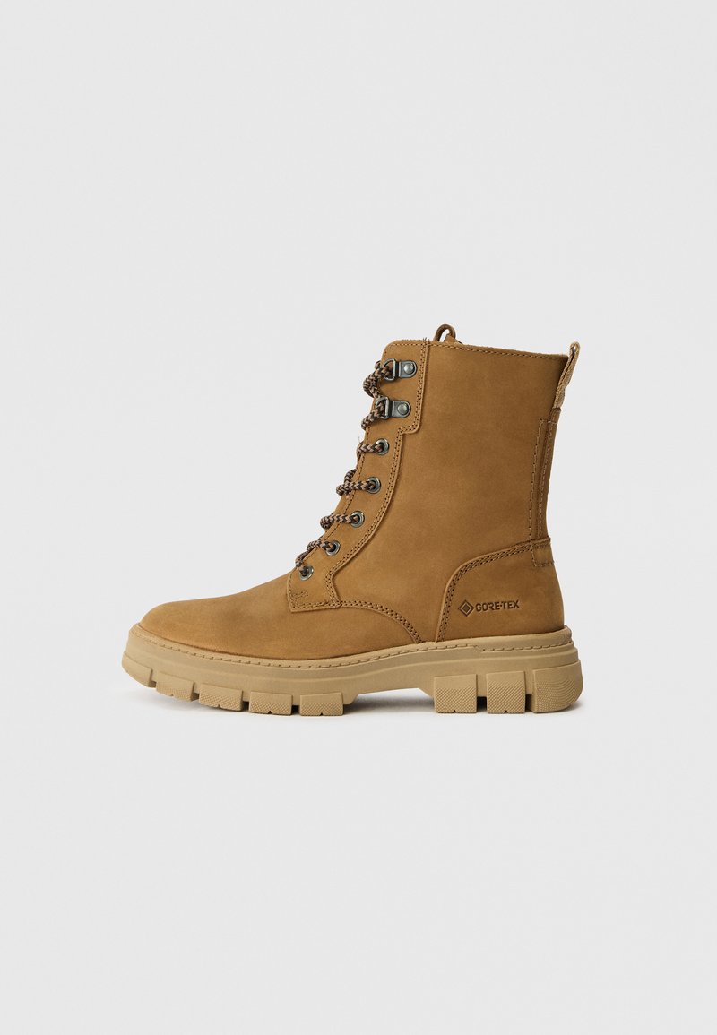 Braune Wildleder-Stiefeletten mit gepolstertem Schaft, Metallösen und braunen Schnürsenkeln. Mit einer strukturierten Gummisohle und einem Logo-Detail.