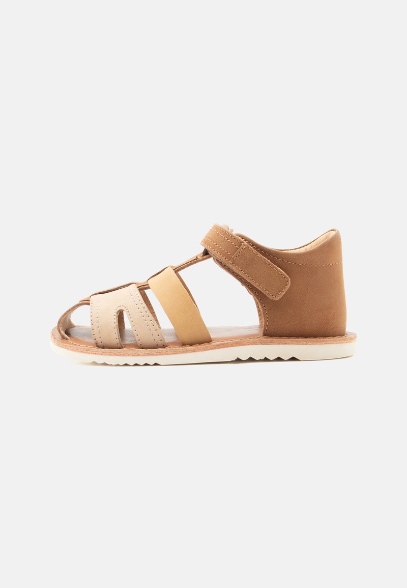 Kindersandale aus braunem und beige Leder mit verstellbarem Knöchelriemen und offenem Zehendesign vor weißem Hintergrund.