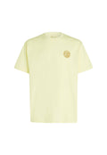 Kurzärmeliges T-Shirt aus leichtem Stoff in zartem Gelb, mit rundem Ausschnitt und einem goldfarbenen, runden Logo auf der linken Brust.