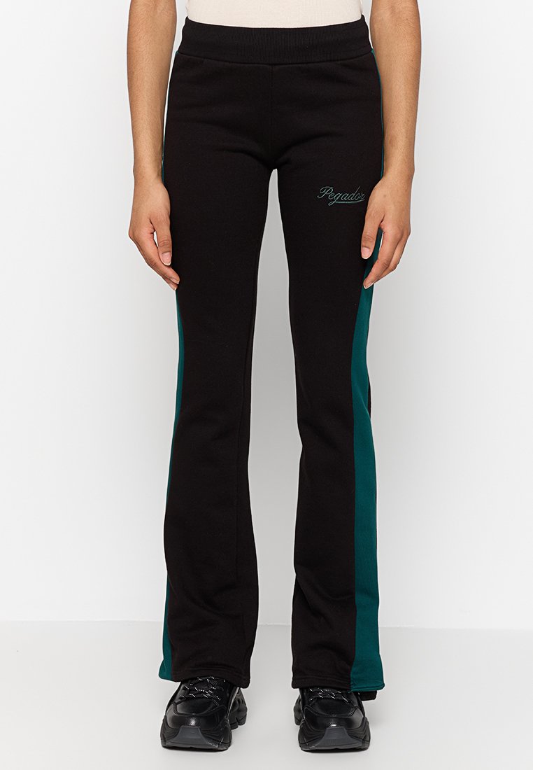 Schwarze, ausgestellte Jogginghosen mit türkisfarbenen Seitenstreifen, aus weichem Stoff gefertigt. Mit einem elastischen Bund und kleinem aufgesticktem Logo.