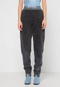 Schwarze Denim-Jogginghosen mit Acid-Wash-Finish, ausgestattet mit einem dehnbaren Bund und abgestuften Knöcheln, kombiniert mit blauen Schuhen.